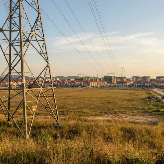 Pentingnya Pengujian Radiasi Elektromagnetik (SUTT/SUTET) untuk Proyek Properti & Industri Meta Description: Pengujian radiasi elektromagnetik SUTT/SUTET wajib bagi proyek properti & industri dekat jaringan transmisi listrik. Simak regulasi terbaru, standar aman, dan prosedurnya. Mengapa Isu Ini Semakin Relevan bagi Pengembang Properti dan Industri Pertumbuhan kawasan properti, kawasan industri, dan fasilitas produksi di Indonesia sering kali tidak bisa dihindarkan dari keberadaan jaringan Saluran Udara Tegangan Tinggi (SUTT) maupun Saluran Udara Tegangan Ekstra Tinggi (SUTET). Bagi pengembang, pemilik lahan, maupun pelaku industri yang lokasinya berdekatan dengan jalur transmisi ini, memahami tingkat radiasi elektromagnetik di sekitar area proyek bukan lagi sekadar isu kesehatan masyarakat, melainkan juga menyangkut kepatuhan regulasi, kelayakan lahan, dan potensi kompensasi yang perlu diperhitungkan sejak tahap perencanaan. Aturan Terbaru: Permen ESDM No. 13 Tahun 2025 tentang Ruang Bebas Jaringan Transmisi Pemerintah melalui Kementerian ESDM menerbitkan Permen ESDM Nomor 13 Tahun 2025 yang diundangkan pada akhir April 2025, menggantikan Permen ESDM 13/2021 sebelumnya. Aturan ini secara khusus mengatur ruang bebas jaringan transmisi tenaga listrik, yaitu area di sekeliling dan sepanjang konduktor SUTT/SUTET yang wajib bebas dari aktivitas tertentu demi keselamatan masyarakat dan keandalan operasi jaringan listrik. Beberapa poin penting dari regulasi ini yang perlu diperhatikan pengembang properti dan pelaku industri: Lahan di bawah ruang bebas sebenarnya masih dapat dimanfaatkan pemiliknya, namun karena ada pembatasan penggunaan, pemilik lahan berhak menerima kompensasi dari pemilik jaringan—bukan berupa ganti rugi, melainkan penggantian dengan mekanisme dan penilaian tertentu. Penilaian besaran kompensasi kini dilakukan oleh Lembaga Penilai atau Kantor Jasa Penilai Publik (KJPP) yang independen berdasarkan pemenuhan perizinan berusaha, menggantikan mekanisme lama yang ditunjuk langsung oleh Kementerian. Proses pemeriksaan rencana jalur transmisi kini dilakukan lebih rinci dan transparan melalui sistem daring, untuk menghindari ketidaksesuaian antara dokumen dan kondisi di lapangan. Regulasi ini juga menegaskan larangan sejumlah aktivitas di sekitar ruang bebas, seperti mendirikan bangunan atau menanam tanaman yang memasuki ruang bebas, menambang atau menimbun tanah di bawah jaringan, hingga menerbangkan drone atau balon udara di sekitar area transmisi. Bagi proyek properti dan kawasan industri yang berada di dekat jalur SUTT/SUTET, memahami batas ruang bebas dan potensi kompensasi ini menjadi bagian penting dari studi kelayakan lahan sebelum pembangunan dimulai. Standar Batas Aman Paparan Medan Elektromagnetik Selain aspek ruang bebas, aspek kesehatan dan keselamatan tetap menjadi perhatian utama. Medan listrik dan medan magnet yang timbul di sekitar konduktor tegangan tinggi merupakan alasan utama mengapa keberadaan ruang bebas ini penting dan harus disesuaikan dengan standar nasional maupun internasional. Batas aman paparan radiasi elektromagnetik di Indonesia mengacu pada rekomendasi WHO dan ICNIRP (International Commission on Non-Ionizing Radiation Protection), yang menetapkan ambang batas untuk medan listrik (V/m) dan medan magnet (µT atau mG) yang aman bagi manusia dalam paparan jangka panjang. Perlu dipahami bahwa medan elektromagnetik dari SUTET beroperasi pada frekuensi sangat rendah (50 Hz), yang secara prinsip fisika berbeda dari radiasi pengion seperti sinar-X. Energi pada frekuensi ini tidak cukup untuk merusak struktur sel secara langsung, namun paparan jangka panjang pada intensitas tinggi tetap perlu dipantau, terutama untuk bangunan yang akan dihuni atau dioperasikan dalam durasi lama di sekitar jalur transmisi. Mengapa Proyek Properti dan Industri Wajib Melakukan Pengujian Ini Kepatuhan perizinan dan studi kelayakan Hasil pengukuran radiasi elektromagnetik menjadi salah satu data pendukung dalam dokumen lingkungan (UKL-UPL/AMDAL) maupun kajian teknis kelayakan lahan, terutama jika lokasi proyek berjarak dekat dengan jaringan SUTT/SUTET. Penentuan zona aman dan tata letak bangunan Data pengukuran memungkinkan pengembang menentukan zona aman untuk penempatan bangunan hunian, area produksi, atau fasilitas publik, sehingga desain tapak dapat disesuaikan sejak awal dan menghindari potensi masalah di kemudian hari. Dasar negosiasi kompensasi ruang bebas Bila sebagian lahan proyek masuk dalam ruang bebas jaringan transmisi sesuai Permen ESDM 13/2025, data hasil pengukuran turut mendukung proses penilaian oleh KJPP dalam menentukan nilai kompensasi yang wajar. Mitigasi risiko kesehatan dan reputasi Menyediakan data ilmiah yang transparan kepada calon penghuni, tenaga kerja, atau masyarakat sekitar dapat mengurangi kekhawatiran sekaligus membangun kepercayaan terhadap proyek yang dijalankan. Perlindungan terhadap gangguan sistem elektronik Selain aspek kesehatan, medan elektromagnetik yang tinggi juga berpotensi mengganggu perangkat elektronik sensitif di fasilitas industri, sehingga pengukuran turut membantu perencanaan tata letak peralatan produksi. Metode Pengukuran yang Umum Digunakan Pengambilan data radiasi elektromagnetik pada dasarnya mengukur dua parameter utama: Medan listrik (V/m) — diukur menggunakan elektrometer untuk mengetahui tingkat tegangan listrik di sekitar jaringan tegangan tinggi. Medan magnet (µT/mG) — diukur menggunakan gaussmeter untuk menganalisis intensitas medan magnet yang dihasilkan konduktor. Hasil pengukuran kemudian dianalisis untuk menentukan zona aman, dibandingkan dengan ambang batas WHO/ICNIRP, dan bila diperlukan dilengkapi dengan kajian dampak terhadap masyarakat sekitar sebagai bagian dari studi epidemiologi ringan. Langkah yang Perlu Diambil Pengembang dan Pelaku Industri Sebelum memulai konstruksi atau operasional di lokasi yang berdekatan dengan jalur SUTT/SUTET, sebaiknya lakukan pengukuran radiasi elektromagnetik sejak tahap studi kelayakan, bukan setelah pembangunan berjalan. Selain mempercepat proses perizinan, langkah ini juga membantu menghindari risiko sengketa lahan, komplain masyarakat, maupun revisi desain di tengah jalan yang tentu memakan biaya lebih besar. 📞 Hubungi Kami Segera untuk Konsultasi Perizinan Lingkungan & Pengujian Radiasi Elektromagnetik (SUTT/SUTET): 🌐 Website: www.bimashabartum.co.id 📧 Email: admin.palembang@bimashabartum.co.id 📱 WhatsApp: +62823-7472-2113